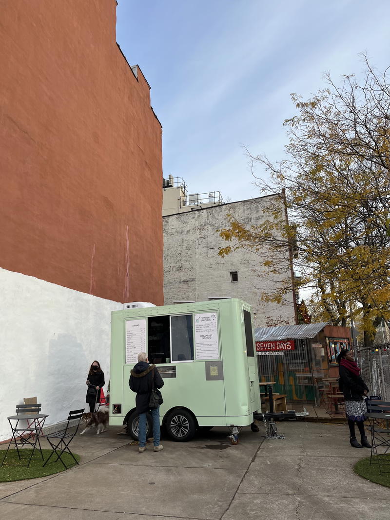 A food truck is parked in front of a building on Blank Street in NYC.