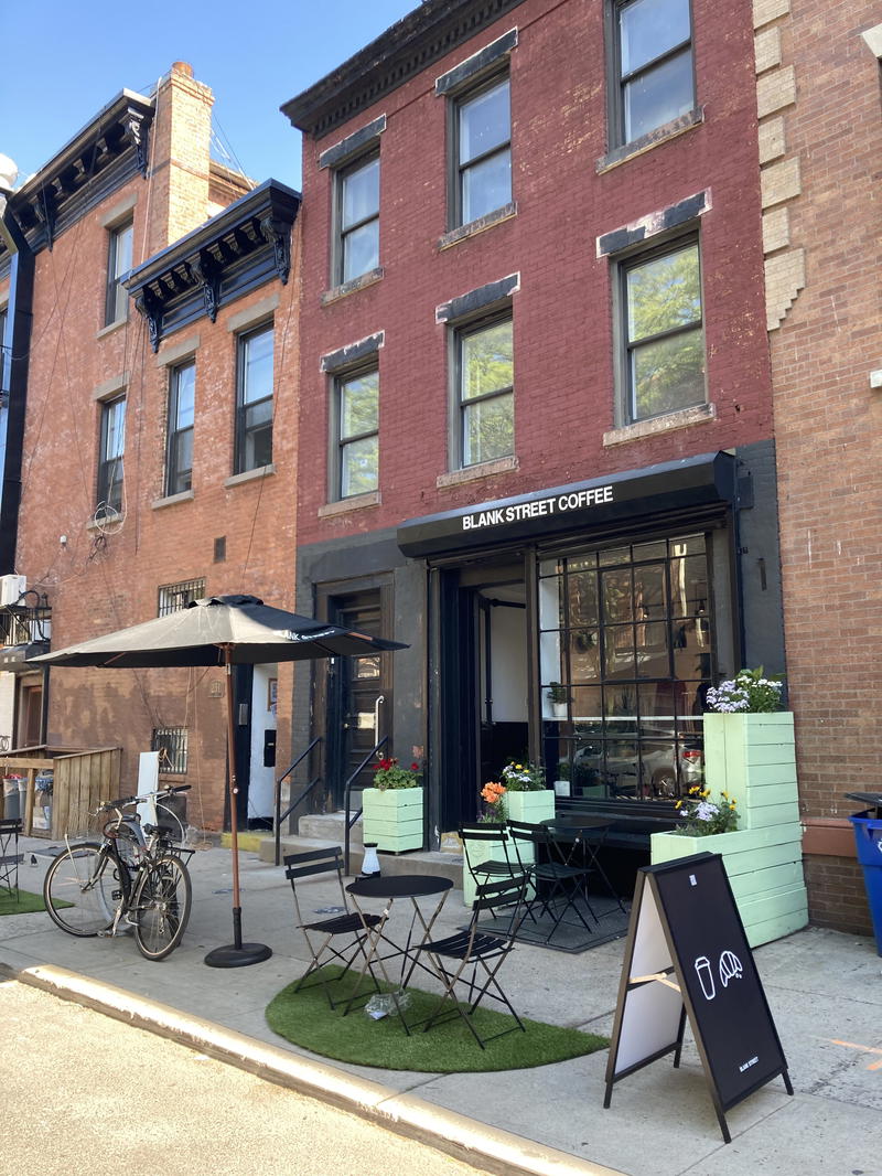 A coffee shop on the corner of Blank Street in NYC with a bicycle in front of it.