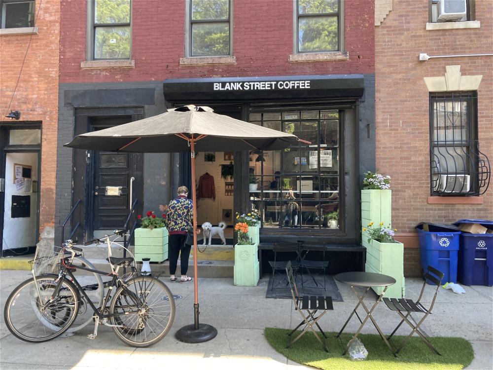 A bicycle is parked outside of a coffee shop in NYC.