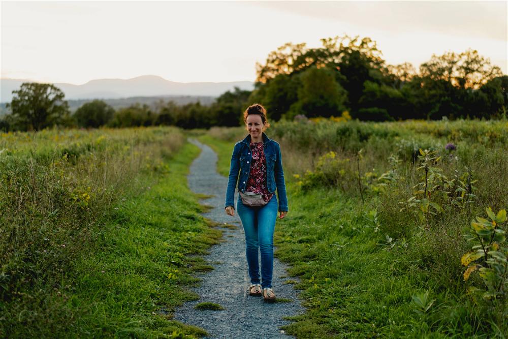 A woman walking down a path in the middle of a field in the Catskills.