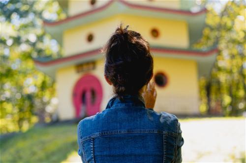 The back of a woman's head in front of a yellow and red Chinese style pagoda
