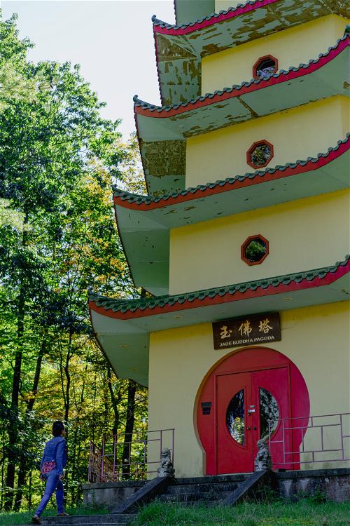 A yellow and green tiered pagoda with a circular red door at the bottom and a sign that reads Jade Buddha Pagoda