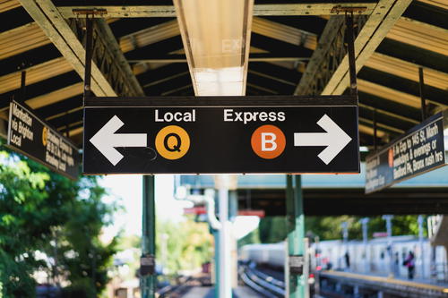 A train station in NYC with a sign that says local express and q.