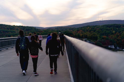 A group of people walking on a bridge in New York City.