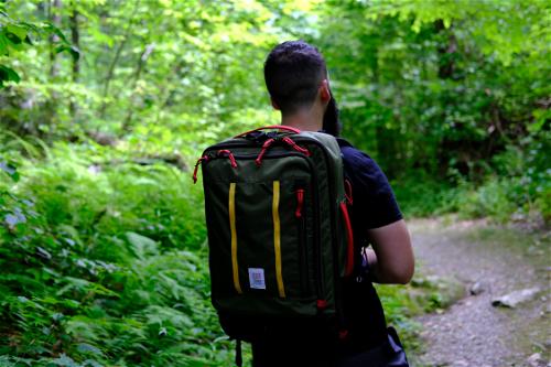 A man walking through the woods near NYC with a backpack.