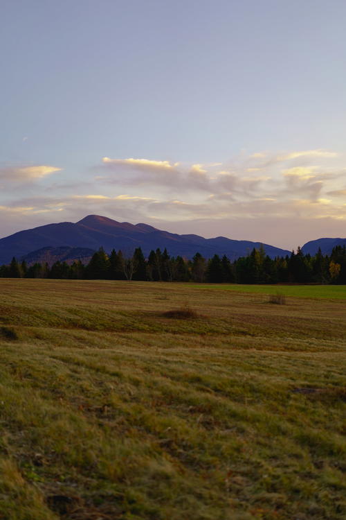 A sunset over a field in the Adirondack Mountains.