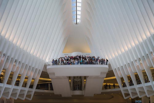 A group of people standing in the middle of a large building in NYC.