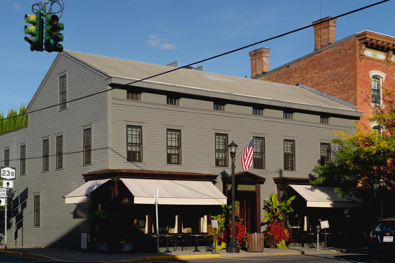 A gray building on the corner of a street in Hudson, New York.