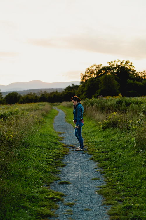 A man is standing on a dirt path in the middle of a field in Hudson, New York.