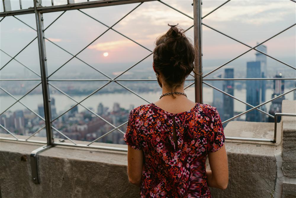 A woman admiring the New York City skyline from the top of the Empire State Building.