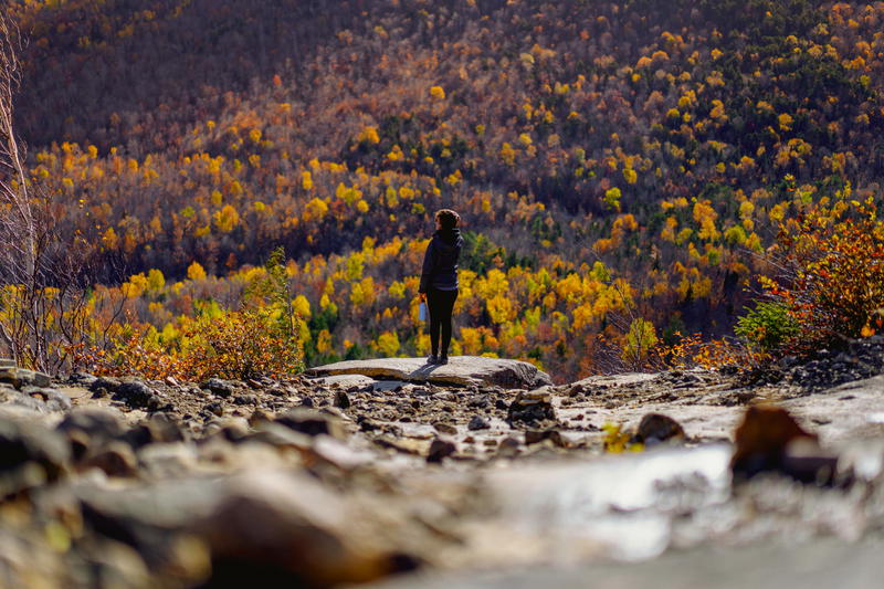 A person standing on top of a rocky hill in Lake Placid, New York.