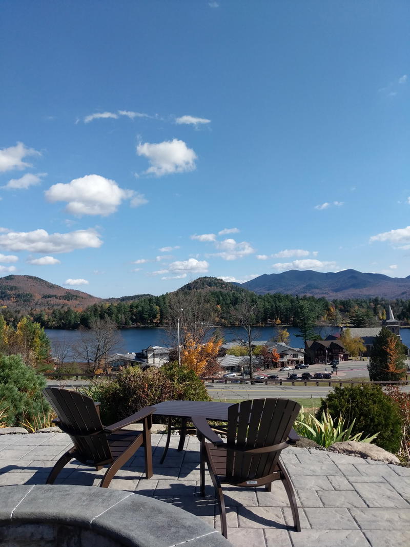 Two chairs on a Lake Placid patio overlooking a lake and mountains in New York.