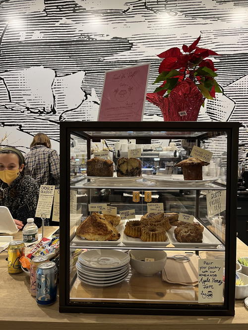 A woman is sitting at a counter in a bakery in NYC.