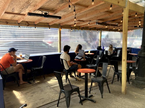 A group of people sitting at tables in an outdoor area in NYC.