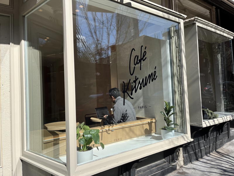 A man is sitting in front of a window with a laptop in NYC.