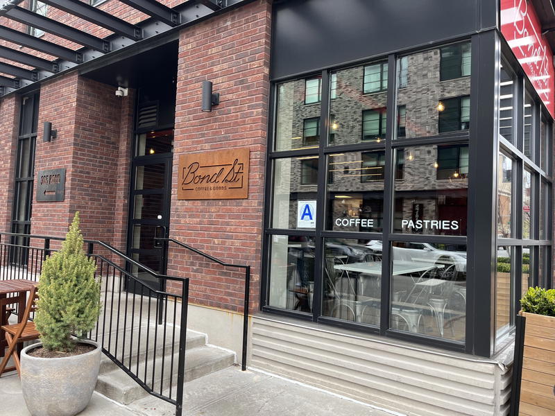 The outside of a NYC restaurant with tables and chairs.