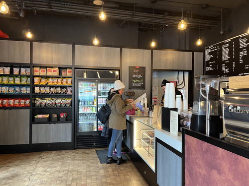 A woman is standing at the counter of a coffee shop in NYC.
