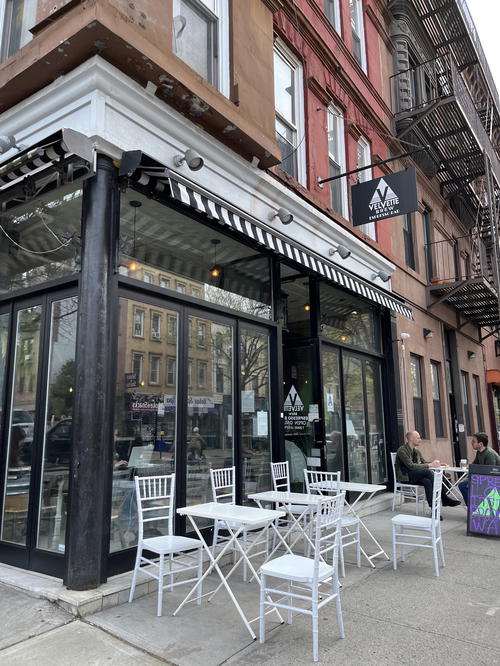 The outside seating area of a NYC restaurant with tables and chairs.