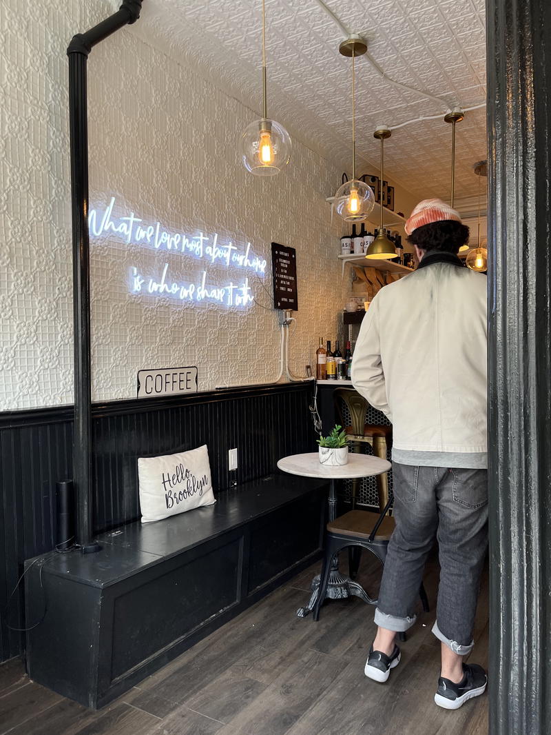 A man walks into a restaurant in NYC with a neon sign.