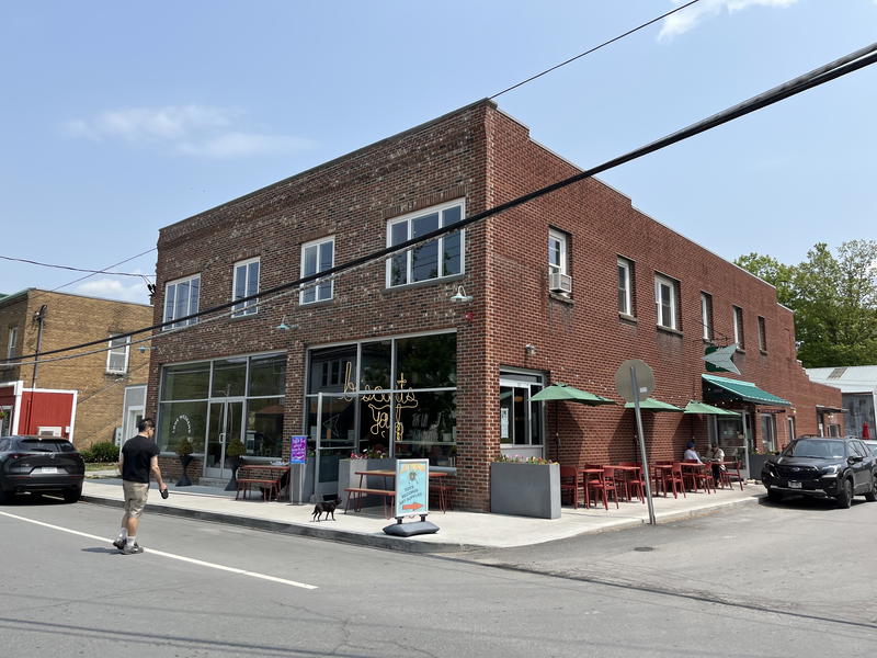 A street corner in Livingston Manor, New York with a brick building and parked cars.