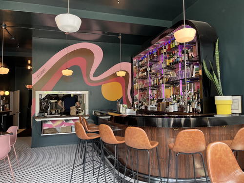 A bar in Livingston Manor, New York with colorful chairs and a colorful mural.