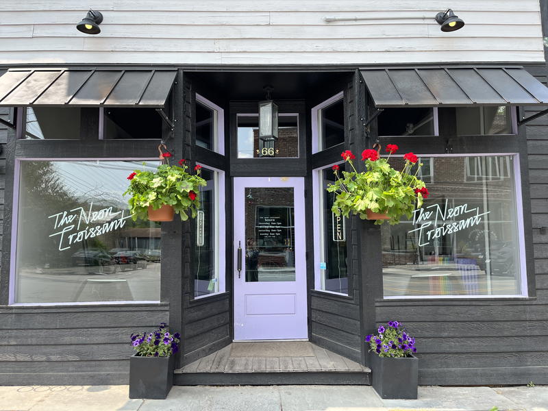 A storefront in Livingston Manor, New York with a purple door and flower pots.