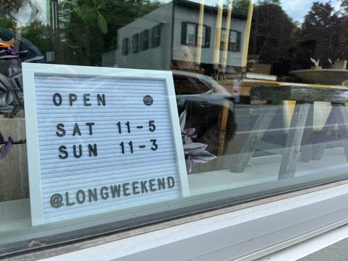 A store in Livingston Manor, New York displays a sign in the window indicating open on weekends.