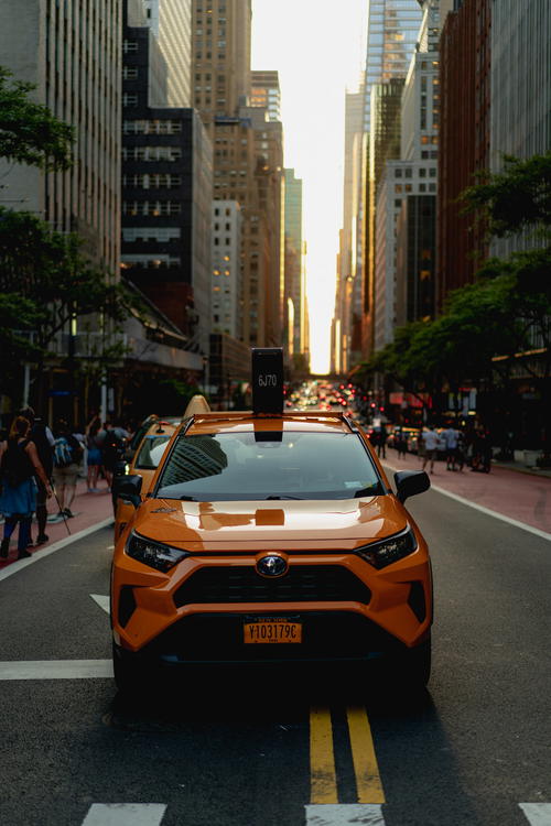 An orange Toyota Hyundai parked on a city street in NYC.