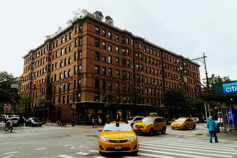 A yellow taxi parked in front of a brick building in NYC.