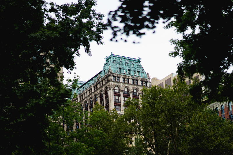 A building with a green roof in the middle of New York City.