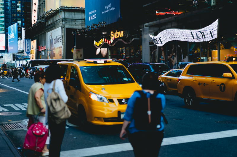A group of people walking on a busy street in NYC.