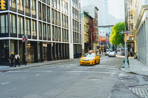 A NYC taxi driving down a city street.
