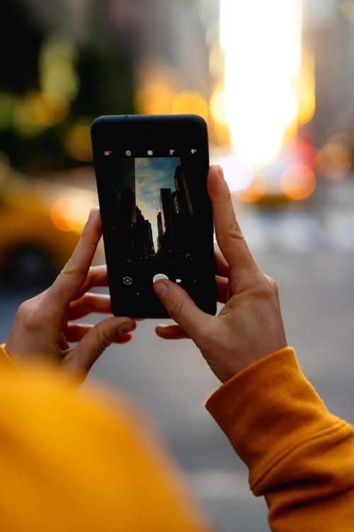 A person taking a picture in Manhattan with a cell phone.