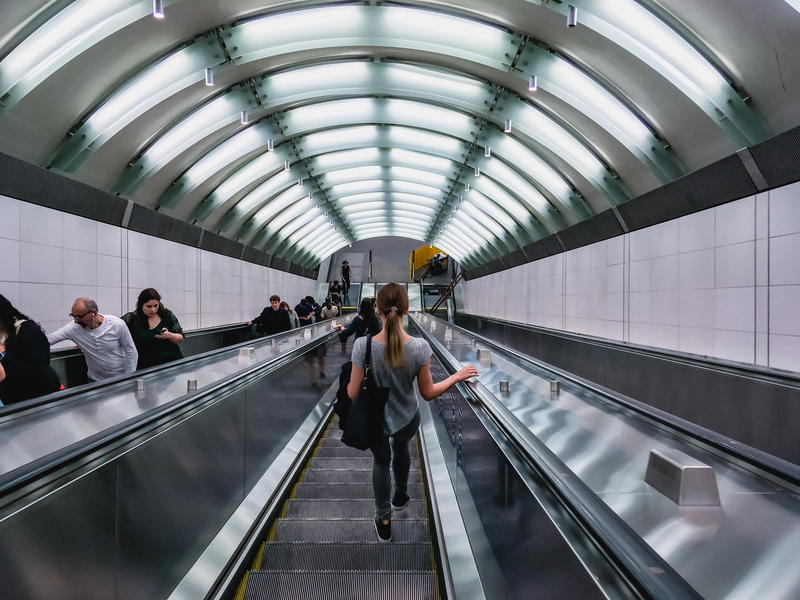 A woman is walking down an escalator in a subway station in NYC.