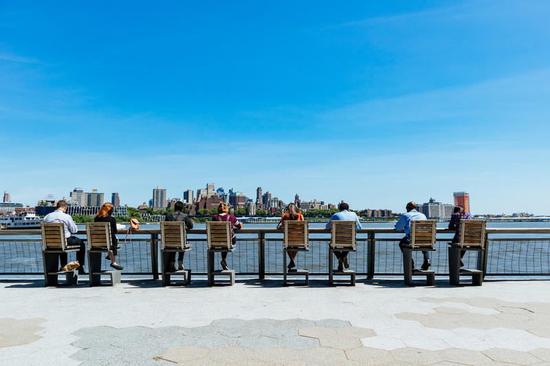 People sitting at the water eating lunch in Battery Park.