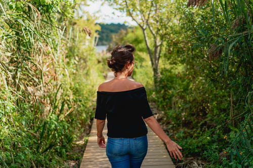 A woman strolling along a boardwalk in Saugerties, New York's wooded area.
