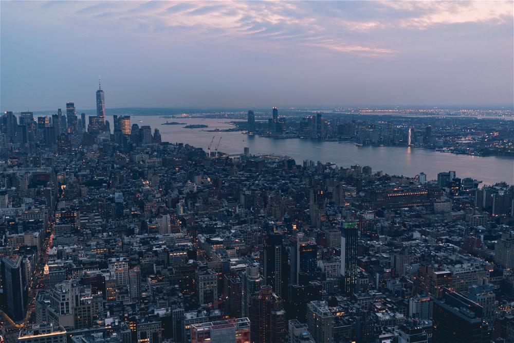 An aerial view of New York City, including the Empire State Building, at dusk.