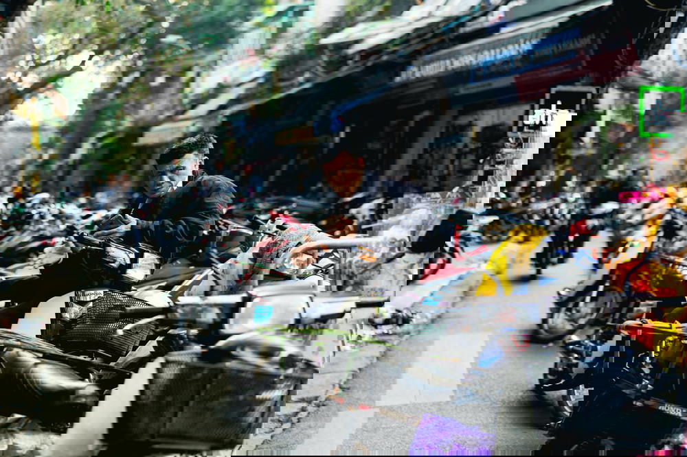 In Vietnam's crowded streets of Hanoi, a man sits on a motorcycle.