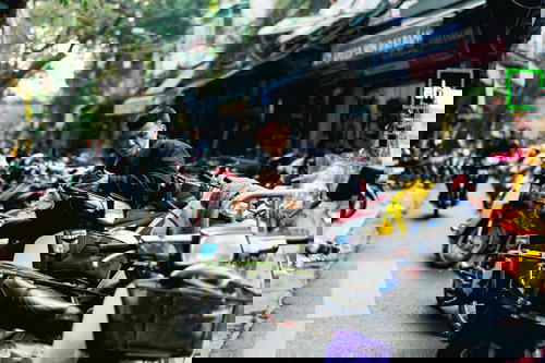 In Vietnam's crowded streets of Hanoi, a man sits on a motorcycle.