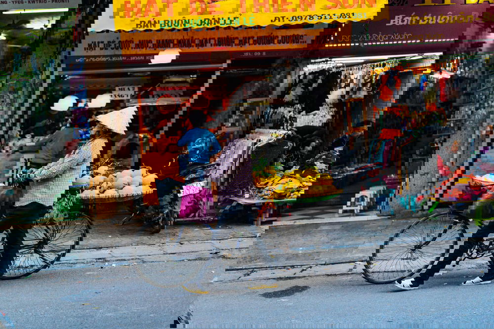 Woman walking her bike on the streets of Hanoi