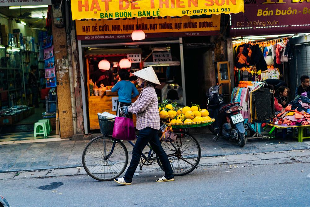 Woman walking her bike on the streets of Hanoi