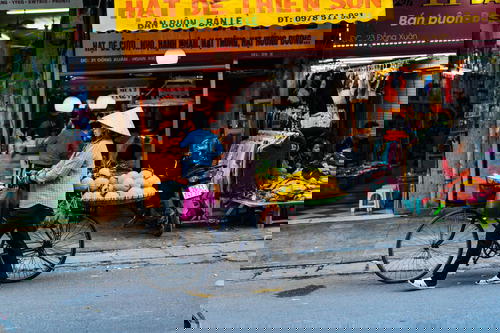 Woman walking her bike on the streets of Hanoi