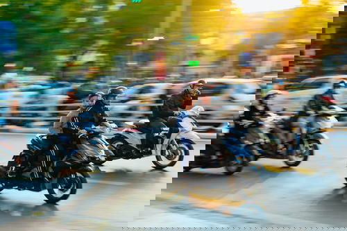 A group of people riding motorcycles on the busy streets of Hanoi, Vietnam.
