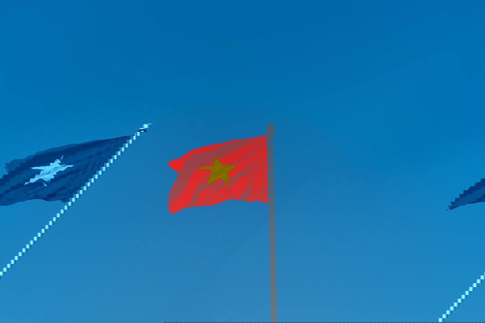 A Vietnam flag flutters against a Hanoi skyline.