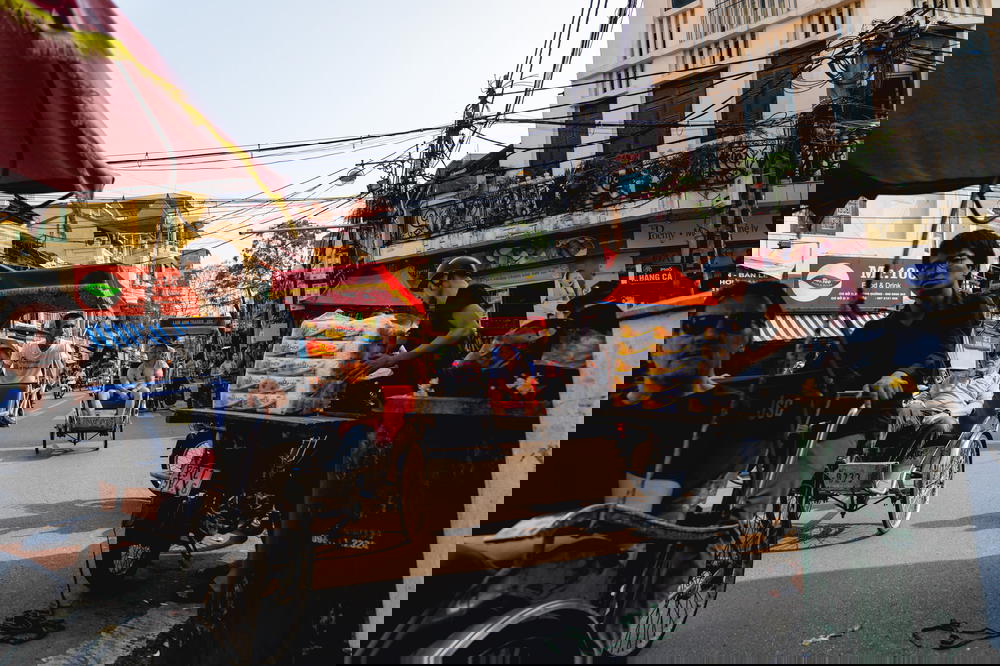 A group of people riding a tuk tuk through the streets of Hanoi in Vietnam.