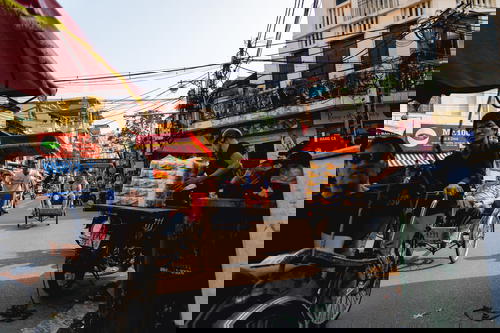 A group of people riding a tuk tuk through the streets of Hanoi in Vietnam.