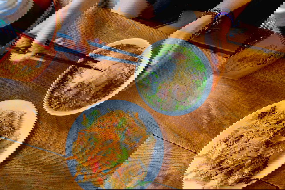 A woman in Hanoi, Vietnam is holding chopsticks while eating a bowl of food.