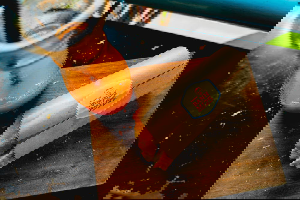 A sandwich from Vietnam on a cutting board next to a glass of orange juice.