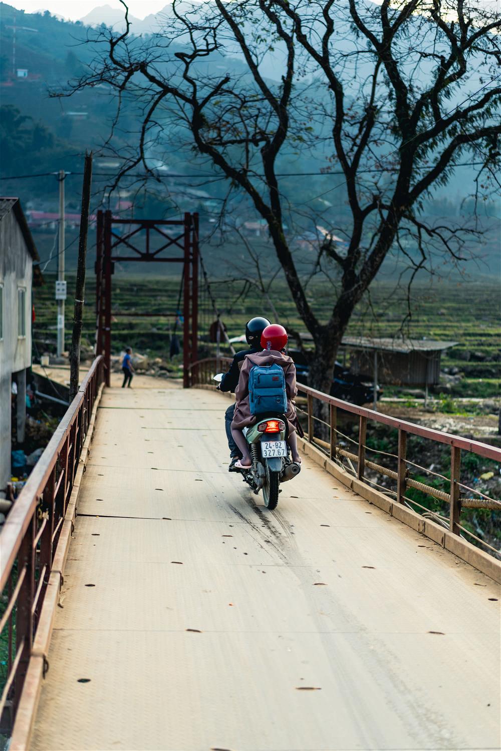 Driving moto over bridge near rice terraces of Sapa Vietnam