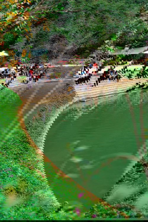 Visitors sit on stone steps next to the pond and river at Hoa Lu Vietnam